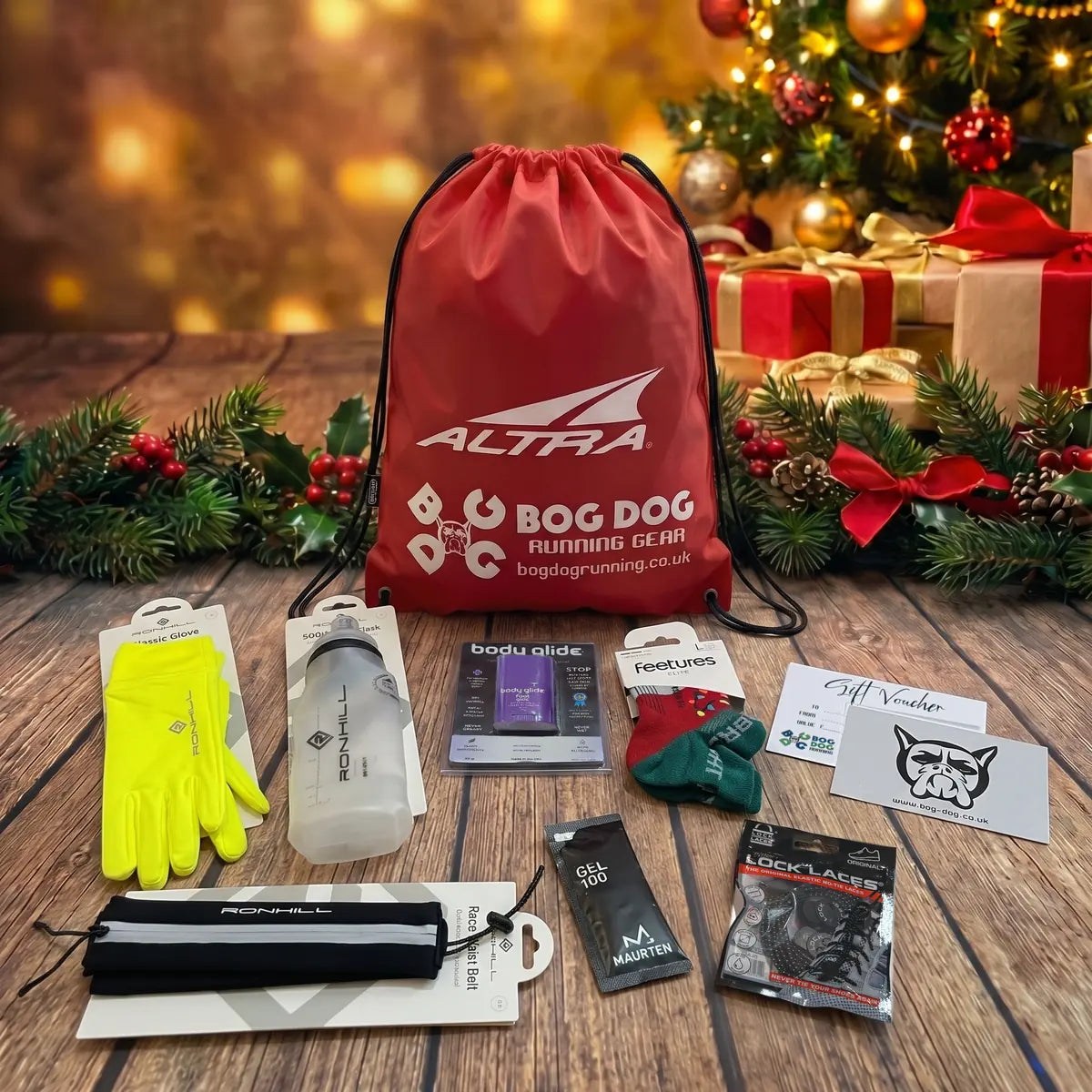 Gold runner’s Christmas gift set: Bog Dog gift voucher, Ronhill Classic Gloves, Fuel Flask and Race Waist Belt, Lock Laces, Feetures Elite Christmas socks, Body Glide Foot Glide and a Maurten Gel 100 with a red Bog Dog and Altra drawstring bag